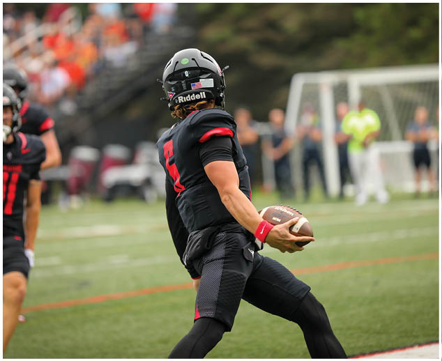A football player in a black jersey with the number 12 on it. Description generated by AI