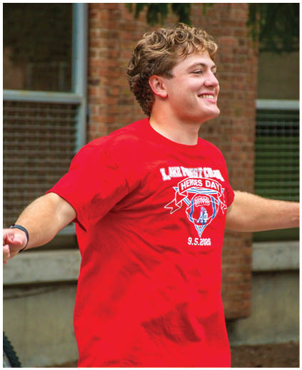 A man wearing a red shirt with the words “Lake of the woods" on it. Description generated by AI