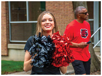 A woman holding a red and black cheerleader's pom poms. Description generated by AI