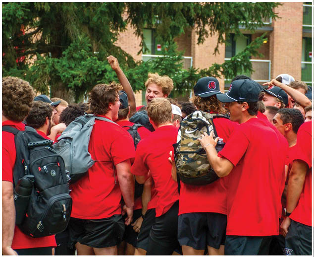 A group of people wearing red shirts and black shorts. Description generated by AI