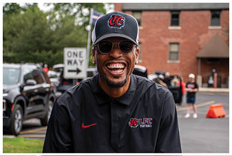 A man wearing a black and red shirt and a black hat. Description generated by AI