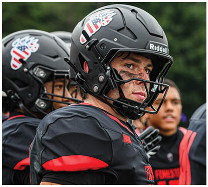A football player wearing a black and red jersey. Description generated by AI