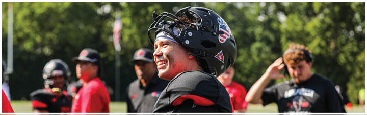 A football player wearing a helmet and a red jersey. Description generated by AI