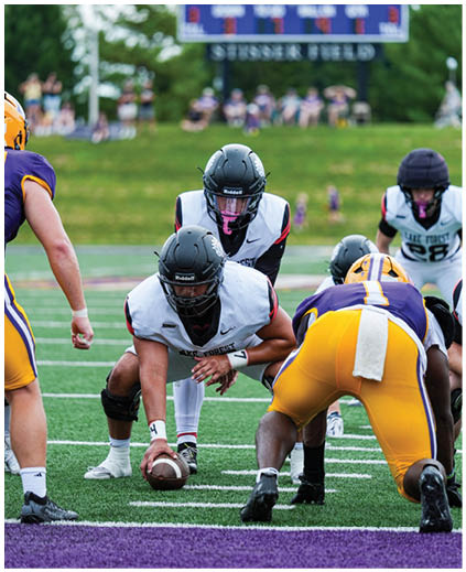A football game is taking place on a field with a scoreboard in the background. Description generated by AI