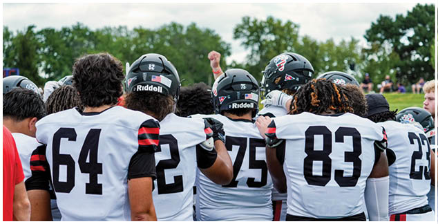 A group of football players wearing white and black uniforms. Description generated by AI
