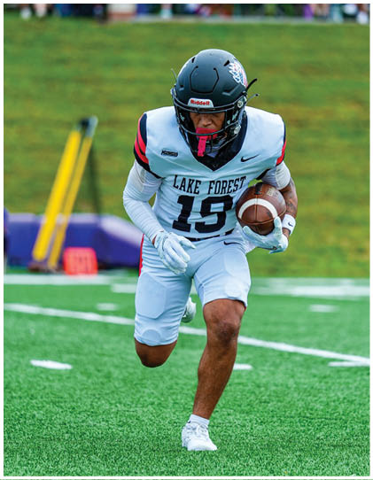 A football player running with a football. Description generated by AI