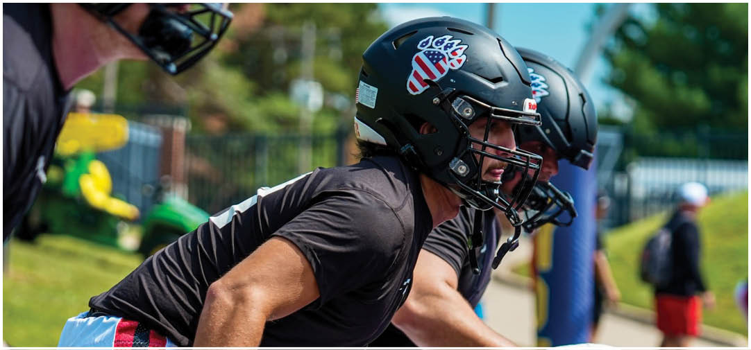 Three football players wearing black and red uniforms. Description generated by AI