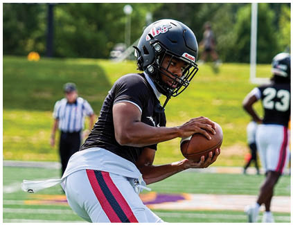 A football player in a black shirt and white shorts is running with a football. Description generated by AI