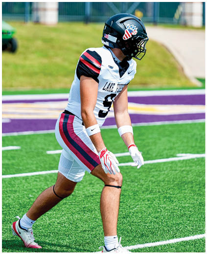 A football player wearing a black helmet and white uniform. Description generated by AI