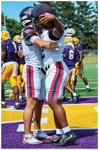 Two men wearing red and white uniforms hugging each other. Description generated by AI