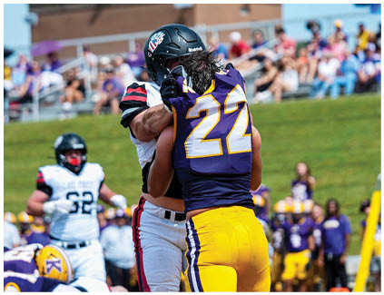 Two football players on a field. Description generated by AI