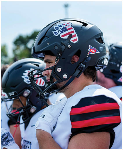 A football player wearing a helmet with an American flag on it. Description generated by AI