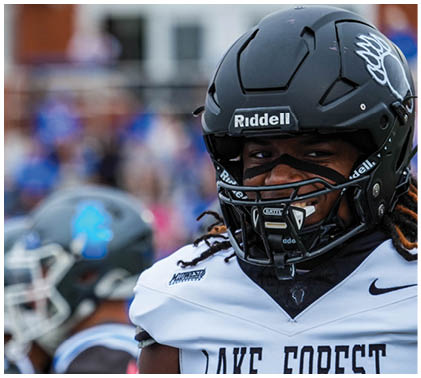 Two football players wearing helmets and jerseys. Description generated by AI
