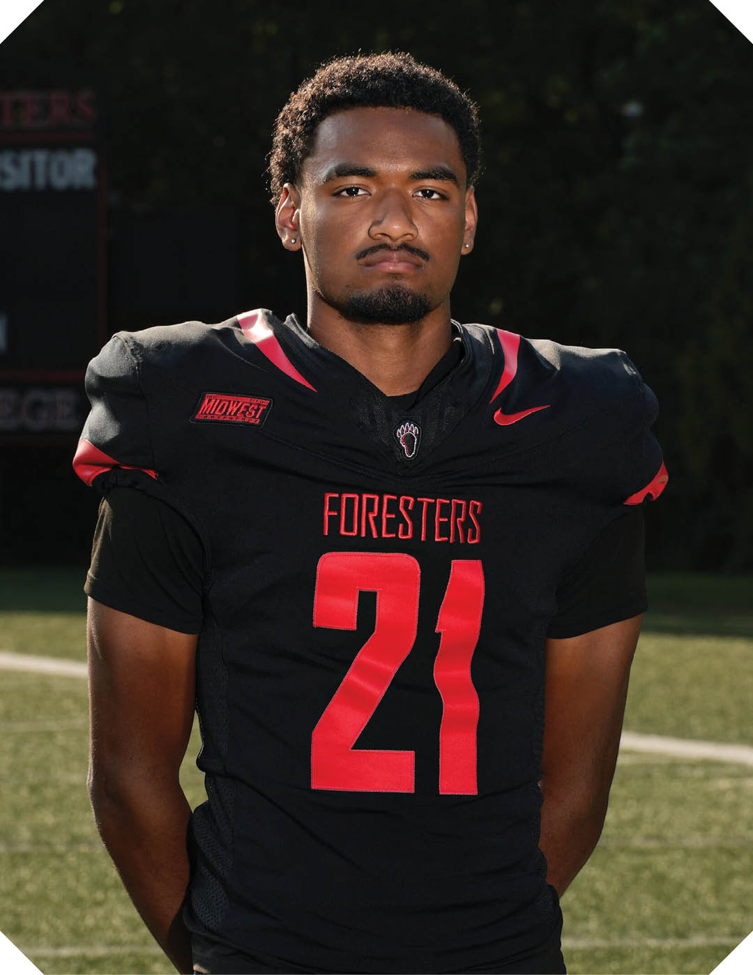 A young man wearing a black and white jersey with the word Vista on it stands on a field. AI generated content