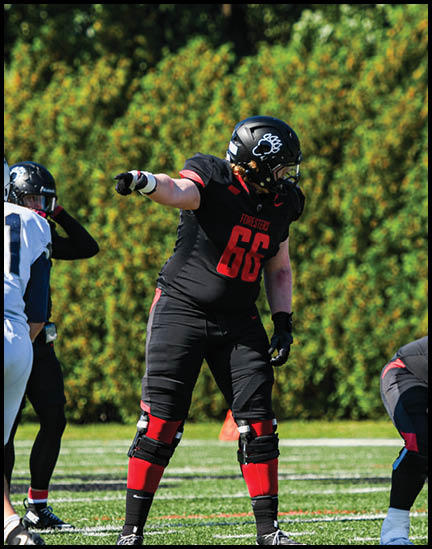 A football player wearing a black jersey with the number 11 on it. Description generated by AI