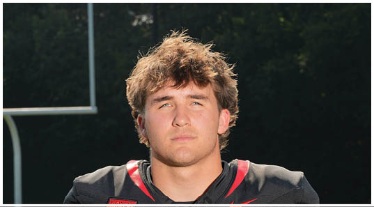 A football player wearing a blue and red jersey. Description generated by AI