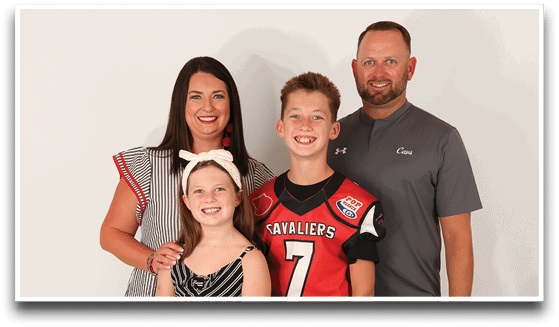 Three adults wearing football jerseys with the number 3 pose smiling against a dark background, with one holding a football. Description generated by AI