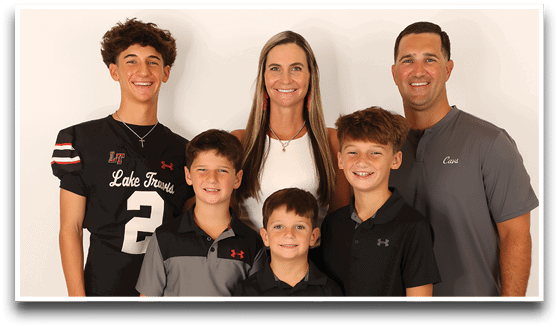 Three adults wearing football jerseys with the number 3 pose smiling against a dark background, with one holding a football. Description generated by AI