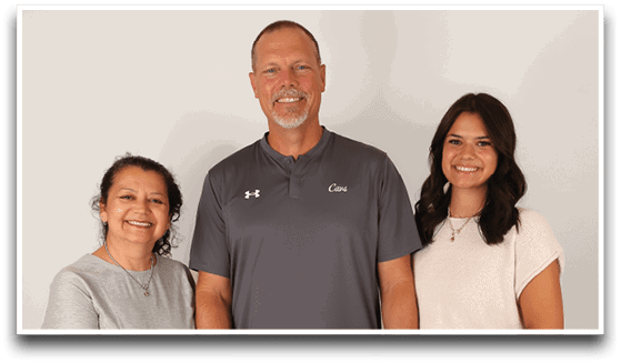 Three adults wearing football jerseys with the number 3 pose smiling against a dark background, with one holding a football. Description generated by AI