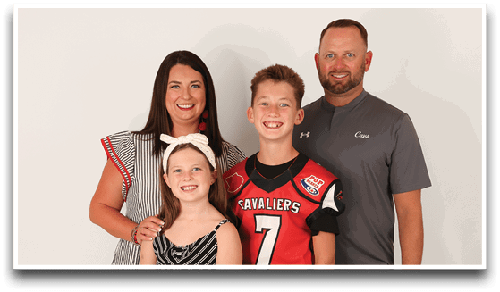 Three adults wearing football jerseys with the number 3 pose smiling against a dark background, with one holding a football. Description generated by AI