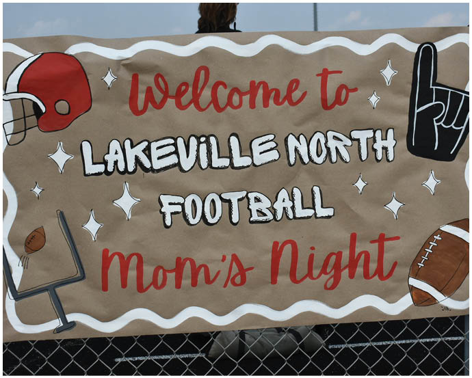 A decorative banner with football-themed illustrations welcomes attendees to Lakeville North Football Mom's Night. Description generated by AI