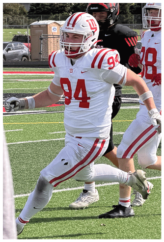 A person wearing a white and red football uniform with the number 84 is running on a green turf field. Description generated by AI