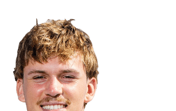 A person with short curly hair wearing a white football jersey with the number seven is holding a football and standing on a sports field. Description generated by AI