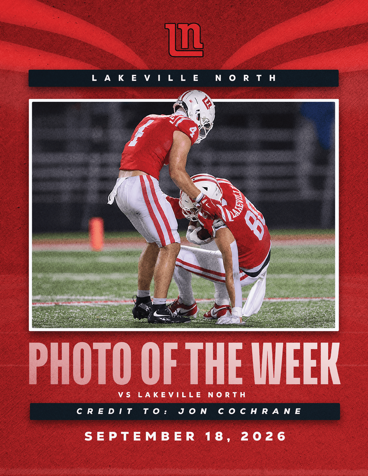 Two athletes in red and white football uniforms are on a field with one helping the other to stand, featured as the photo of the week for Lakeville North with a date of September 18, 2026. Description generated by AI