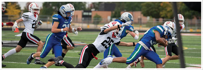 People wearing helmets and sports uniforms are actively running and competing on a football field. Description generated by AI