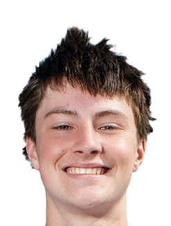 A person with short, spiky dark hair is smiling directly at the camera against a white background. Description generated by AI