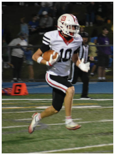 A person wearing a white football uniform with the number 10 is running on a football field while holding a football. Description generated by AI