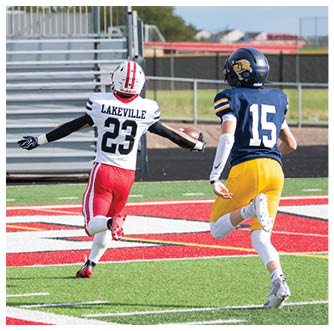 Two people in football uniforms are running on a field toward the end zone near an orange marker with the number 10. Description generated by AI