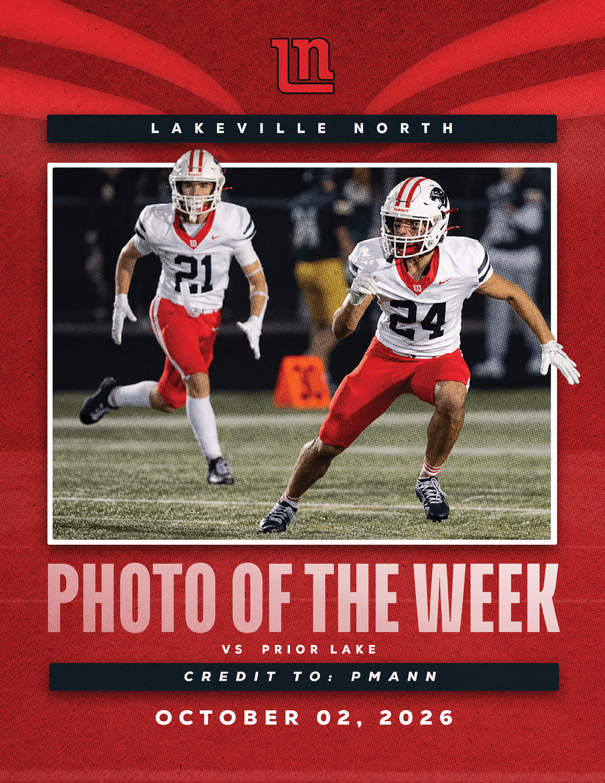 Two athletes in football uniforms with helmets and red pants are running on a field during a game between Lakeville North and Prior Lake. Description generated by AI