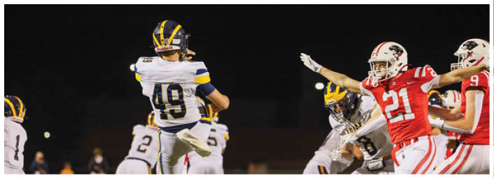 A person wearing a white sports jersey with the number 49 is preparing to throw a football during a nighttime game. Description generated by AI