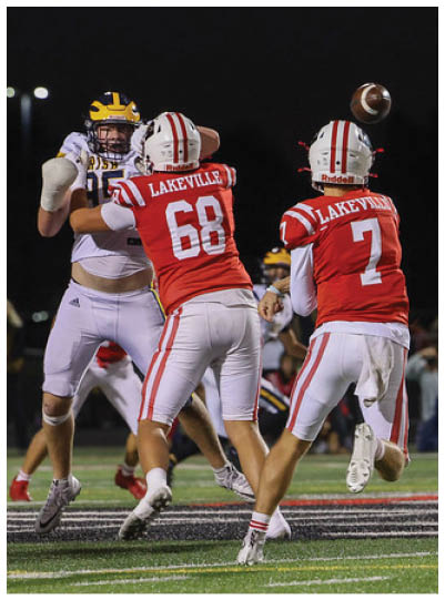 People wearing football uniforms are actively playing on a field during a nighttime game. Description generated by AI