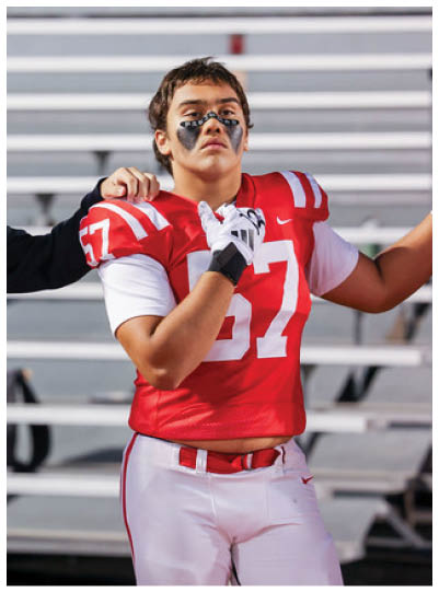 A person wearing a red sports jersey and white pants is shown from the waist to the upper arm. Description generated by AI