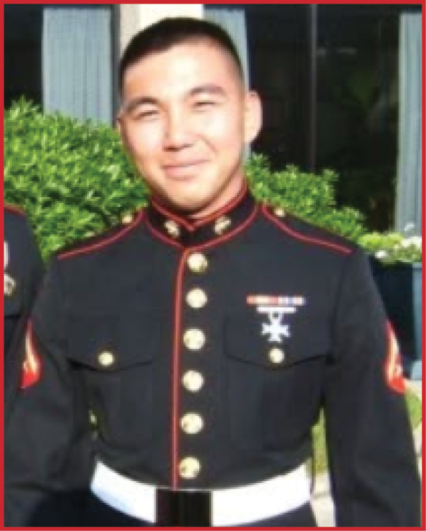 A person wearing a formal military dress uniform with medals stands outdoors in front of greenery and a building. Description generated by AI
