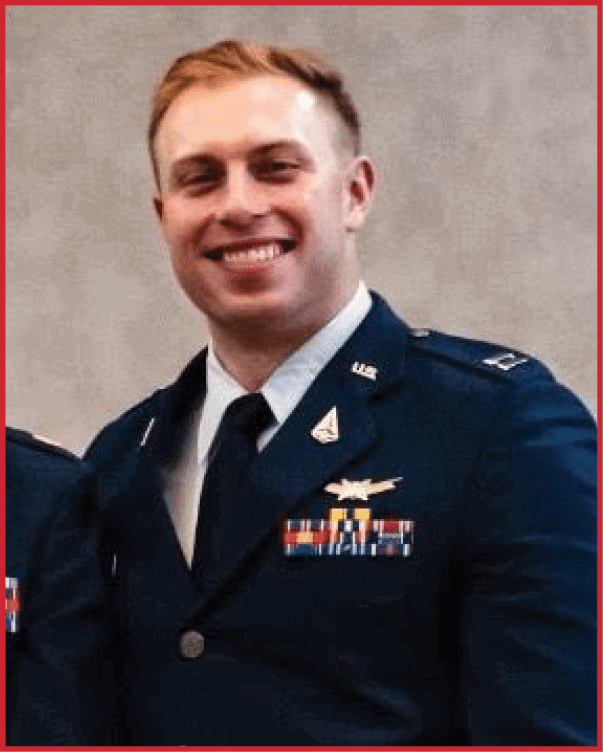 A person wearing a formal military uniform with medals and insignia is smiling against a plain background. Description generated by AI