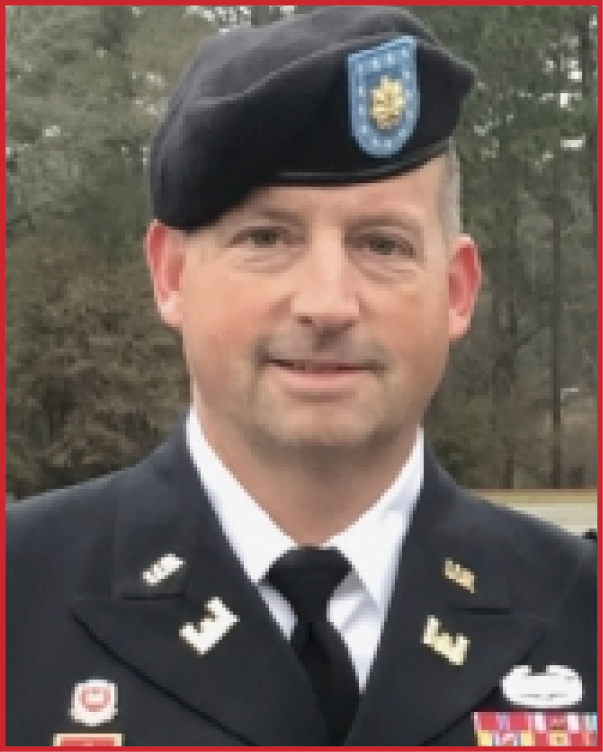 A person wearing a formal military uniform and beret stands outdoors with trees in the background. Description generated by AI