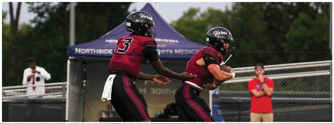 A football game is taking place on a field with players wearing blue and white uniforms. Description generated by AI