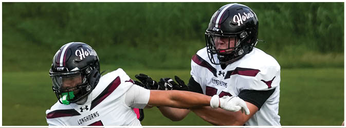 A football game is taking place on a field with players wearing blue and white uniforms. Description generated by AI