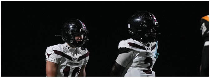 A football game is taking place on a field with players wearing blue and white uniforms. Description generated by AI