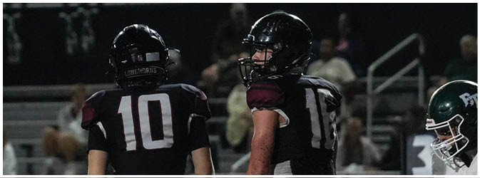 A football game is taking place on a field with players wearing blue and white uniforms. Description generated by AI