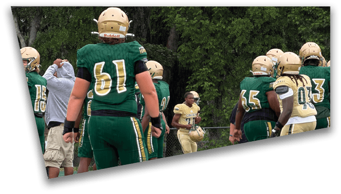 People wearing athletic shoes are standing and walking on a green sports field with white markings. Description generated by AI