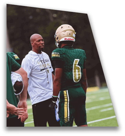 People wearing sports uniforms and casual athletic clothing are standing on a football field engaged in conversation. Description generated by AI