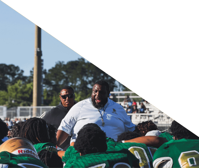 A group of football players kneeling on the field, some with their hands on their heads. AI generated content
