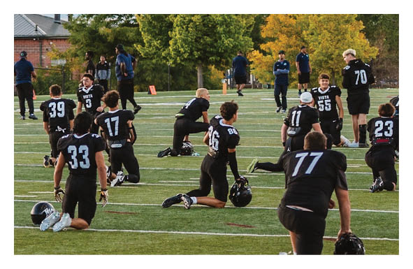A group of people are kneeling on a field, possibly in a football game. AI generated content