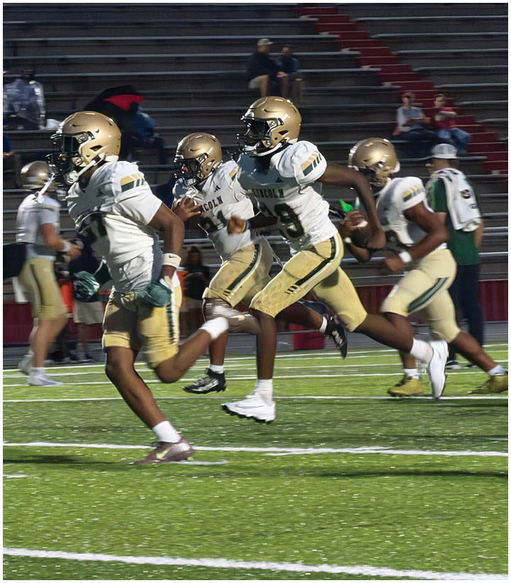 Several people wearing gold helmets and white and gold football uniforms are running on a football field during a game. Description generated by AI