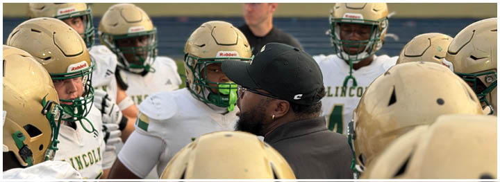 A crowd of people is seated in bleachers watching a football game with two players in helmets visible in the foreground. Description generated by AI