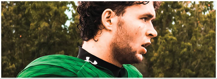 A person wearing a green sports jersey is shown in profile with an intense expression against a background of trees. Description generated by AI